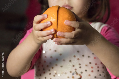Orange. Girl holding an orange. Slices of orange. Two halves. Children's hands. Children. Fruits