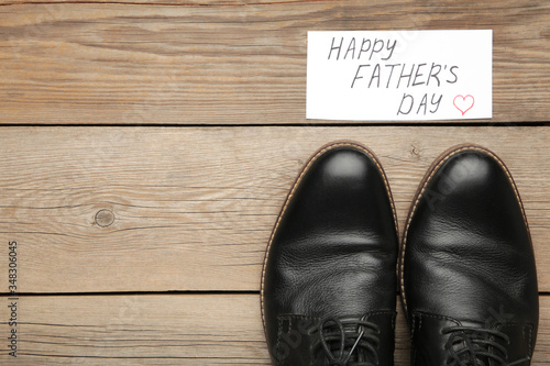 Happy Fathers Day message and black shoes on grey wooden background.