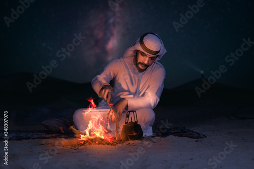 Valokuva Arab young man sitting around bonfire in the desert, Arabic comping, middle east tourism concept