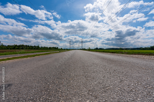 Asphaltstra  e mit Wolken und Strommasten