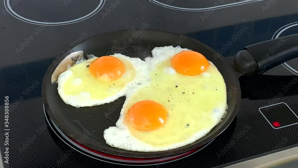 Three eggs with ground pepper frying on pan Three eggs with ground pepper frying on pan
