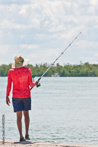 Back view, far distance of, a middle aged, male, fishing on a concrete wall, under a bridge in tropical waters off the gulf of Mexico