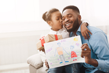 Little girl hugging father and giving handmade drawing