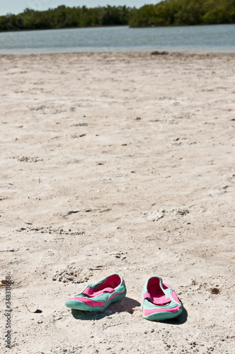 top view, close distance of a pair of colorful, female, sandles in the sand of a tropical beach, on gulf of Mexico on a sunny morning, beach shoes