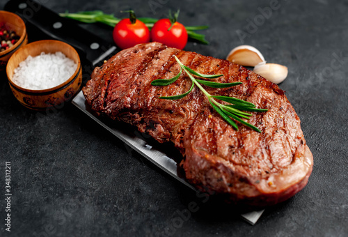 grilled beef steak with spices on a knife on a stone background