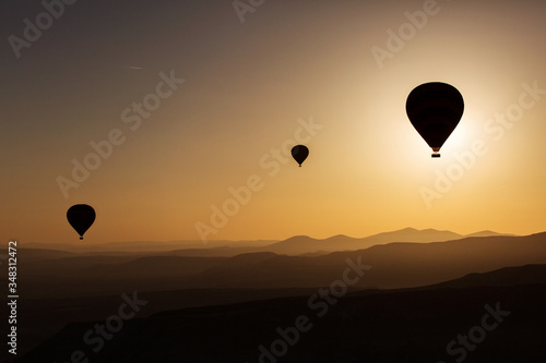 Silhouette of balloons with sunrise in background, aerial view