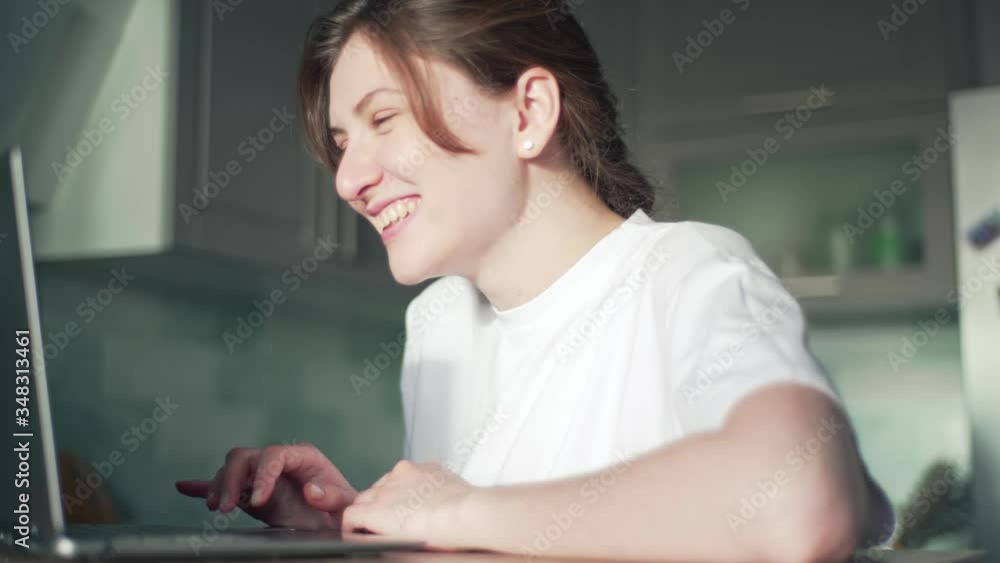 Beautiful woman rejoices in winning the lottery. Girl pleasantly surprised looking at laptop screen. A young freelancer does the work and enjoys the result Beautiful woman rejoices in winning the lottery. Girl pleasantly surprised looking at laptop screen. A young freelancer does the work and enjoys the result