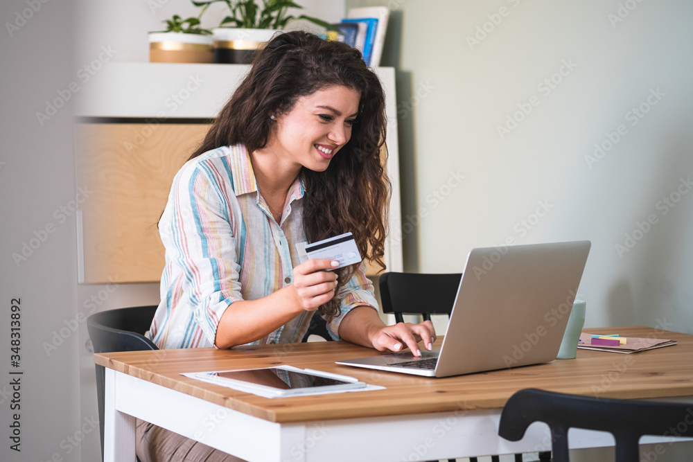 Smiling woman holding credit card and using laptop computer stock photo Smiling woman holding credit card and using laptop computer stock photo
