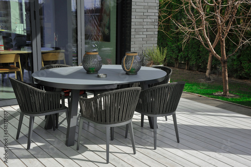 A table and four chairs in the exterior of a country house. Exterior elements