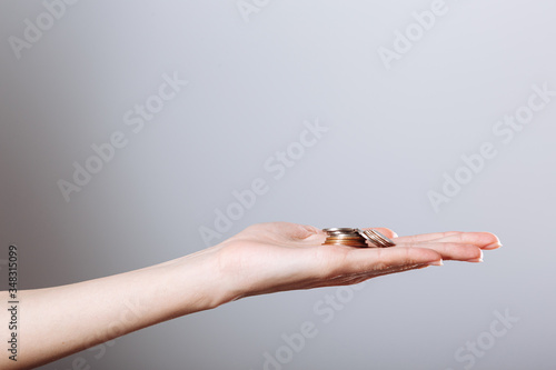 woman's hand holding coins isolated on gray background. Concept crisis, save money