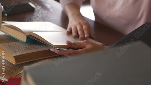 Young Woman Student Reading Text in Paper Book. Girl Pupil is Reading a Book Sitting Home at the Table. Woman Studying. Home Learning. Distance Education. Smart Clever Woman. Knowledge Literature.