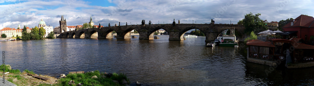 Panorama of Charles Bridge, Prague Gothic Cultural Monument on Vltava river  in Indian summer sun light