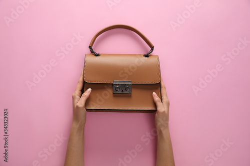 Woman holding stylish handbag on pink background, closeup