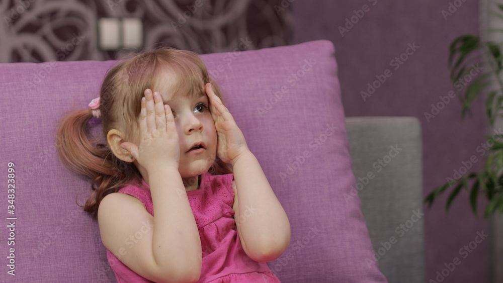 Little child sitting while watching TV. Scared kid girl watch horror movie Little child sitting while watching TV. Scared kid girl watch horror movie