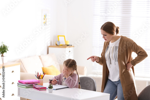 Foto Mother scolding her daughter while helping with homework indoors