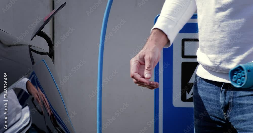 Man disconnect the recharge plug and closes the socket of his electric black car. Alternative energy with car connected and charging batteries close-up 4K Man disconnect the recharge plug and closes the socket of his electric black car. Alternative energy with car connected and charging batteries close-up 4K