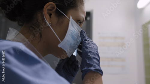 Nurse picking up and putting on mask for coronavirus protection in infection room photo