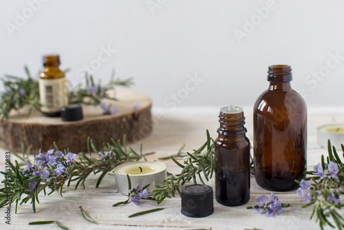 Contenitori di olio essenziale con rametti di rosmarino fioriti photo