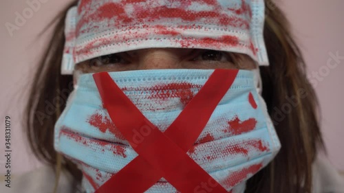 4K Lockdown curfew selfies - Woman looks in hole between two blood-stained masks covering her face
 photo