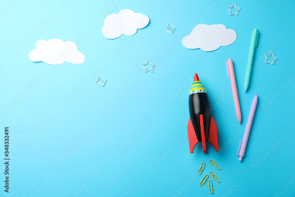 Bright toy rocket and school supplies on light blue background, flat lay. Space for text