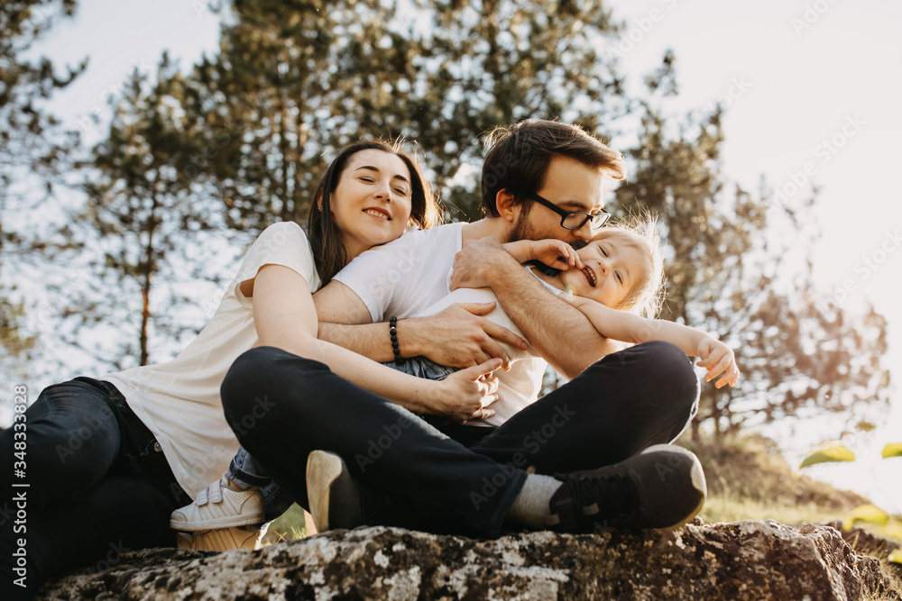 Family of three: man, woman and little girl having fun outdoors. Father kissing daughter on cheek. Family of three: man, woman and little girl having fun outdoors. Father kissing daughter on cheek.