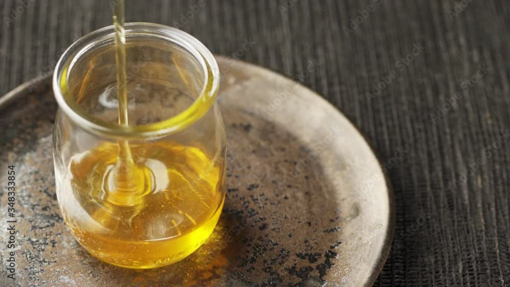 Pouring honey into a glass dish. Jet of liquid honey yellow beautiful pours. close-up. Pouring honey into a glass dish. Jet of liquid honey yellow beautiful pours. close-up.
