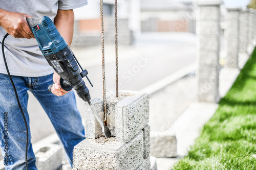 Foto Man worker with pneumatic hammer or drill perforator equipment making hole in bricks wall at construction