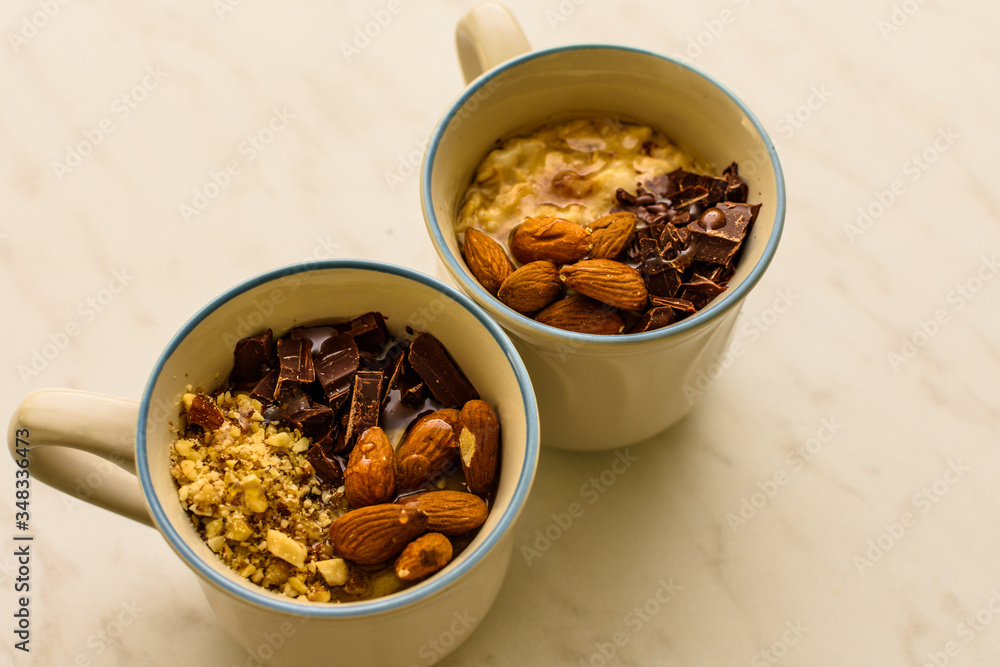 Fototapeta premium Oat porridge in cup for breakfast, on light colored table. Healthy eating, healthy food for breakfast