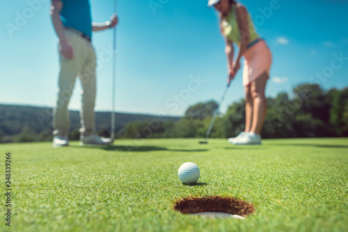 Фотография Couple playing golf with the woman on green to hole in