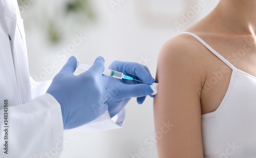 Doctor giving injection to patient in hospital, closeup. Vaccination concept