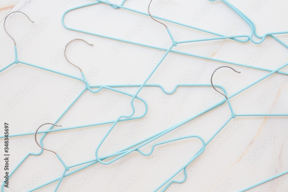  Flat lay set of blue hangers on white marble. Many colored hangers lying chaotically, minimal concept