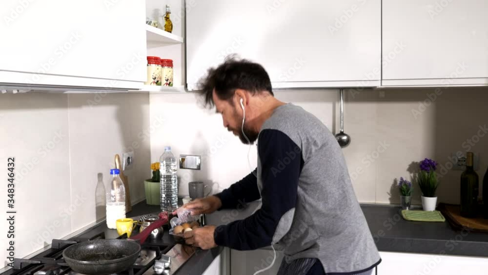 Man during coronavirus isolation quarantine in kitchen in the morning preparing egg Man during coronavirus isolation quarantine in kitchen in the morning preparing egg