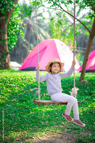 Little girl in pink dress sitting on a swing while camping