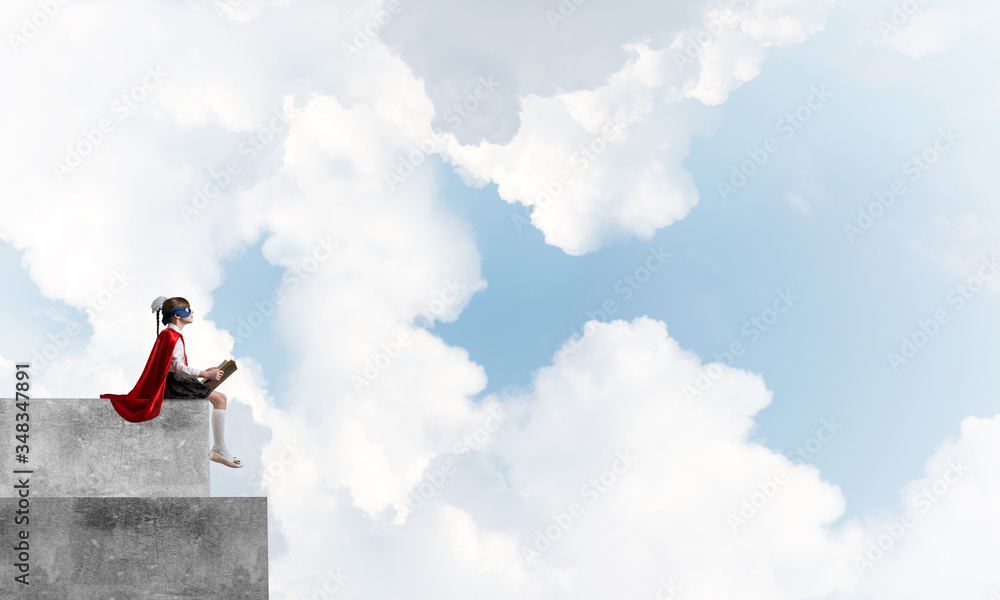 Girl power concept with cute kid guardian against cloudscape background . Mixed media Girl power concept with cute kid guardian against cloudscape background . Mixed media