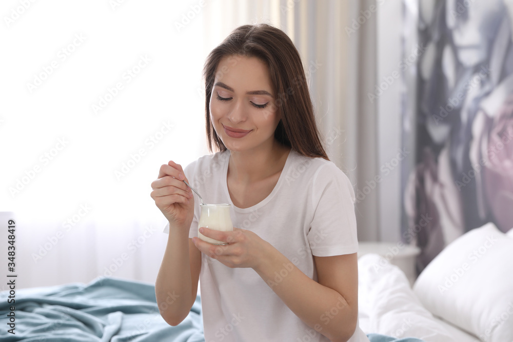 Young attractive woman with tasty yogurt on bed at home Young attractive woman with tasty yogurt on bed at home