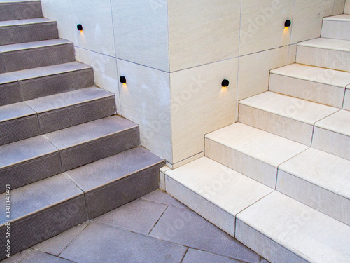 Fotografie Two sets of stairs in opposing colors of black and white meet at the bottom from around a corner