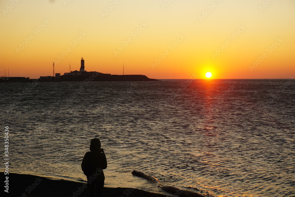 Закат над Черным морем в весенний день. Он поражает своими багровыми красками. Это очень романтично и красиво. Старинный маяк виднеется в золотых лучах.