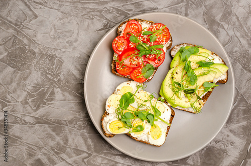 Variety of mini sandwiches with cheese and vegetables on a gray plate, surf dark background.