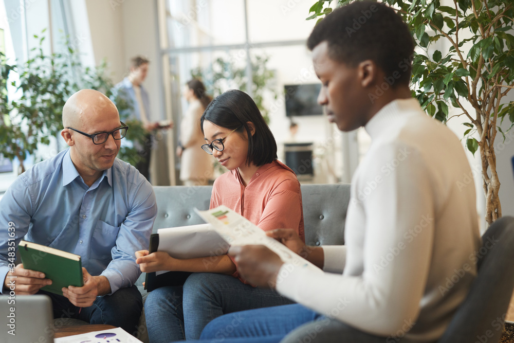 Portrait of multi-ethnic business team working on project in office, focus on smiling Asian businesswoman holding clipboard, copy space Portrait of multi-ethnic business team working on project in office, focus on smiling Asian businesswoman holding clipboard, copy space