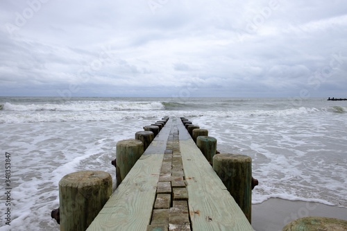 Isolated pier jetty with ocean and sky background. Waves crashing on beach wooden jetty pier. 