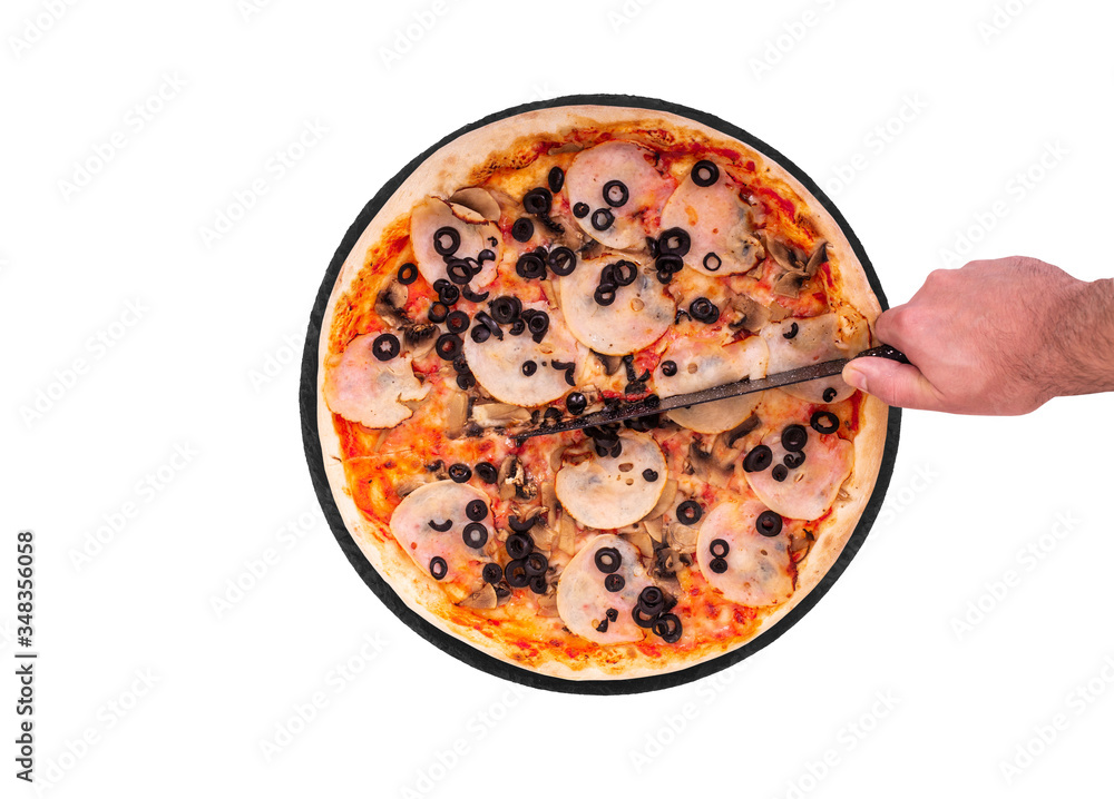 The chef cuts the pizza with a kitchen knife. Tasty pizza with ham, mozzarella, mushrooms and olives on a round slate platter, isolated on white background, top view