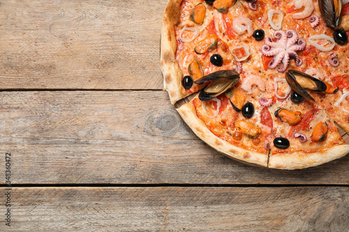Tasty pizza with seafood on wooden table  top view. Space for text