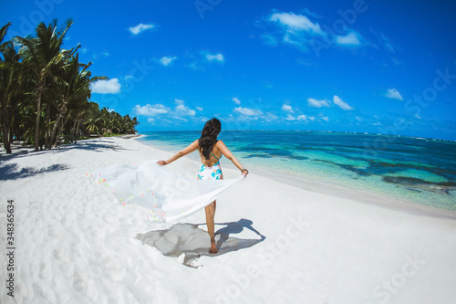 Woman enjoying sunny day on the tropical caribbean sandy beach landscape with turquoise sea and blue sky 