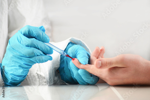 Doctor in protective suit and mask makes a blood sampling with a syringe from a vein of a patient's hand in a hospital. Taking blood samples for analysis. Coronavirus Covid-19 vaccination