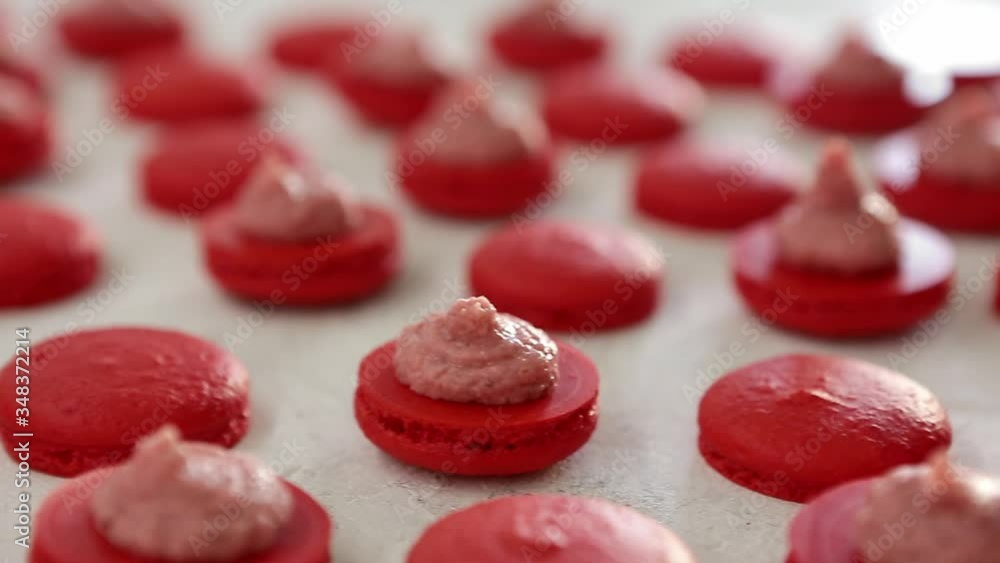 Close-up view of many rows of red opened halves with filling macarons macaroon on white background. Classical French dessert. Close-up view of many rows of red opened halves with filling macarons macaroon on white background. Classical French dessert.