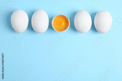 Fresh raw chicken eggs on light blue background, flat lay. Space for text