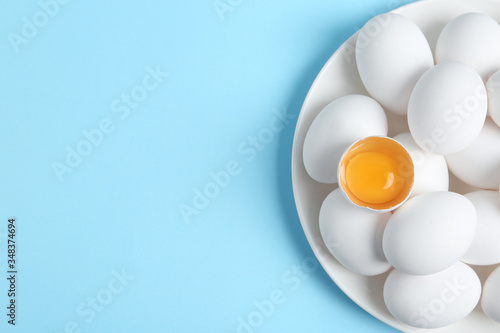Fresh raw chicken eggs on light blue background, top view. Space for text