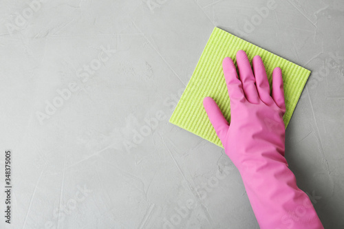 Woman in gloves wiping grey table with rag, top view. Space for text