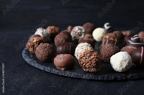 Different tasty chocolate candies on black table