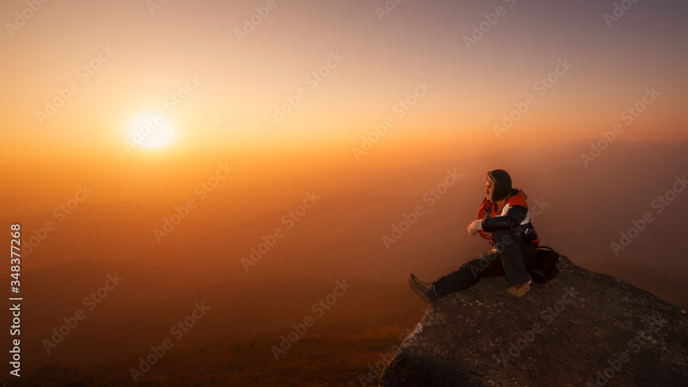man sitting on the rock of high mountain seeing the sunrise